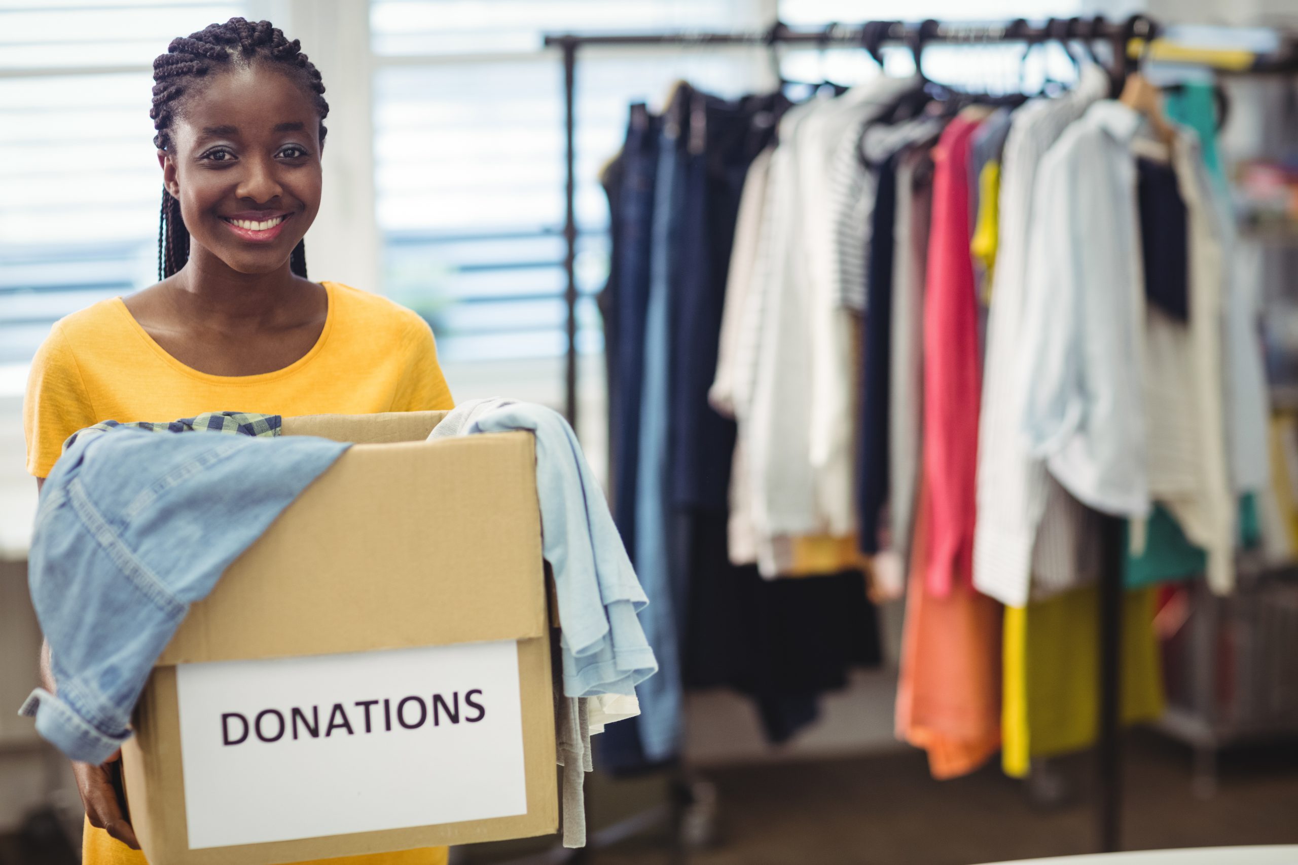 Portrait of female volunteer holding clothes in donation box at workshop
